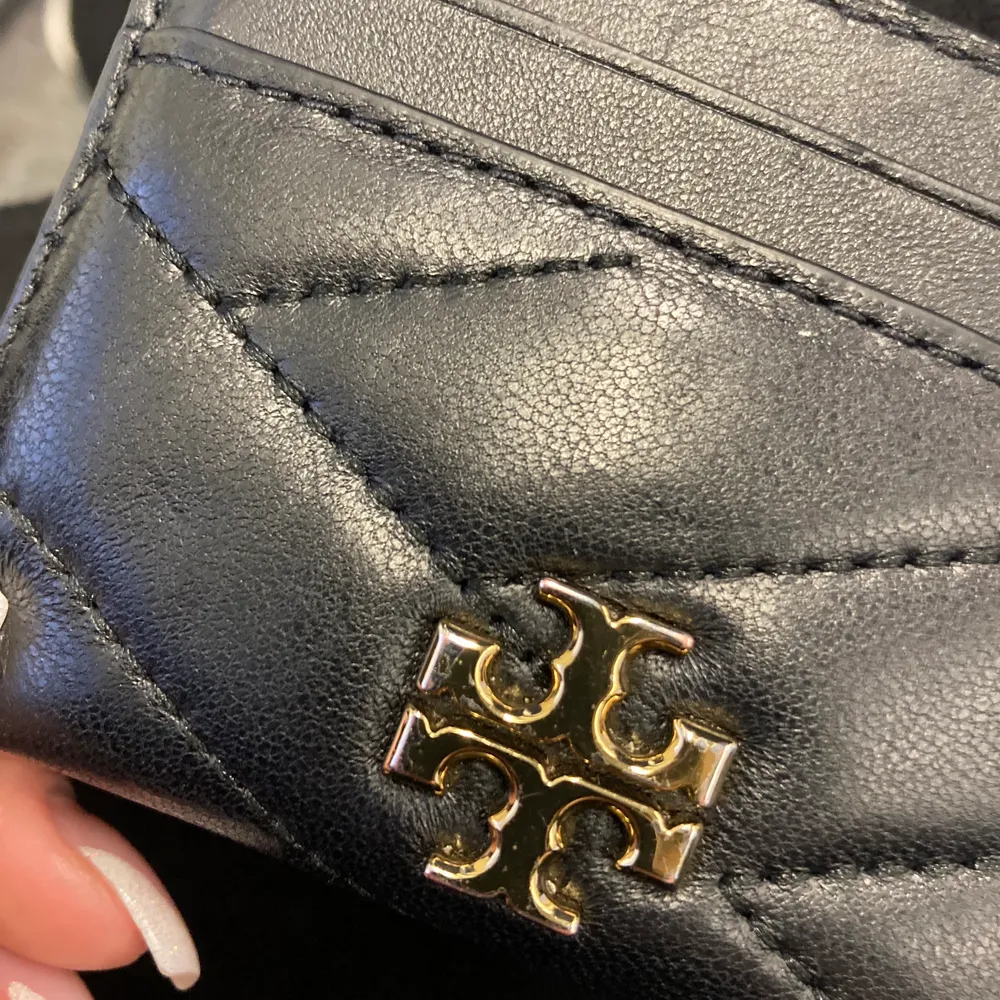 Tory burch korthållare. Den har 2 fack på framsidan, ett mitten fack och 2 fack på baksidan. Den har lite defekt på märket som ni kan se på bild 2. Nypris 1155 . Väskor.