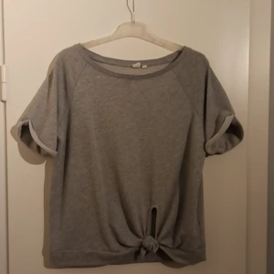 Grå collage tröja från GAP - Det här är en super söt tröja från GAP med upvikta ärmar och en knut på framsidan! Det är i superfint skick och det är bara att höra av sig vid intresse av fler bilder ❤️ köparen står för frakten