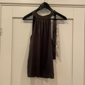 Halternecklinne - Halternecklinne. Grå/svar och rosa/beigt på insidan. Snörning vid nyckelbenet.