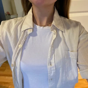 Perfekt trekvartsskjorta  - Plagget är second hand. Storlek M. Tunn beige/benvit skjorta med trekvartsärmar. FRAKTEN ÄR INBAKAD I PRISET 