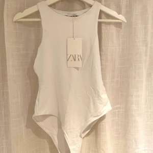 Vit body - Säljer denna snygga body i vitt från zara, väldigt snygg och skön modell. Materialet sitter väldigt snyggt mot kroppen och det är extra tyg över bysten så det inte ska synas igenom:) aldrig använd!