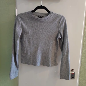 Monki grå ribbad långärmad croppad tröja - Croppad långärmad tröja i grått. Jätteskön men tyvärr för liten för mig numer. Använd ett fåtal gånger, fint skick! Ribbad/våfflad