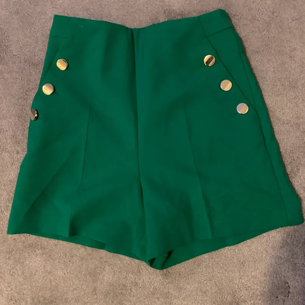 Ett par gröna shorts med guldiga detaljer nyligen köpt från zara med prislappen kvar.     . Shorts.