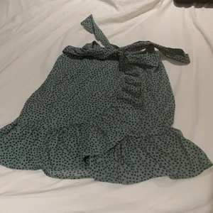 grön kort kjol med svarta små blommor på - En jätte fin kort grön kjol med små svarta blommor på. Använt ungefär 3 gånger.
