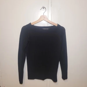 Svart stickad tröja - Ribbad ut på ärmarna och ner från midjan. Lite off-shoulder.