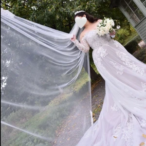 Bröllopsklänning storlek 44-48 - Jag säljer min vackra specialdesignade brudklänning inspirerad av ”Justin Alexander modell 88122”.  En vacker off-white, off-shoulder brudklänning med ärm i storlek 44-48, Den är väldigt lätt att anpassa till egen smak då den är skräddarsydd.   Klänningen är dekorerad i 3 olika spets-tyger som ger en lätt 3D-känsla och som bl.a. framhäver en smalare midja. Klänningen är kemtvättad tillsammans med brudslöja och underkjol. Allting säljes.