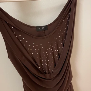 brunt fest linne - ett brunt linne med pärlor och en typ av volang vid bysten 