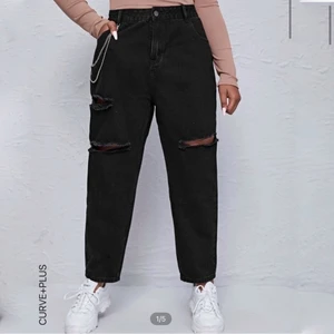 Svarta jeans storlek XXL  - Ett par helt nya svarta jeans med hål i, storlek 1XL från Shein. För stora på mig som har storlek 44-46, så dessa passar nog storlek 48 bättre. Midjemått ca 98 cm. Helt nya som sagt så de har aldrig blivit tvättade. Säljer för det originala priset eftersom de är helt nya. Skönt material med lite stretch i byxan. Kedjan säljer jag tyvärr inte. Frakt ingår ej 