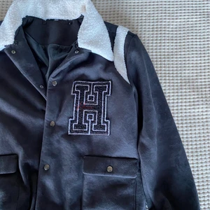 Svart collegejacka med teddykrage - Endast använd ett fåtal gånger och därför i mycket bra skick! Passar både män och kvinnor, men storleken är listad som herrstorlek. Boxig passform.