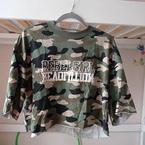 Kort t-shirt storlek L  - En magteöja med militär grön tyg. Är kort i längd men bred i armarna. Har en text på framsidan som säger "regel Girl revolution". (Konstanter mig för frakt pris).