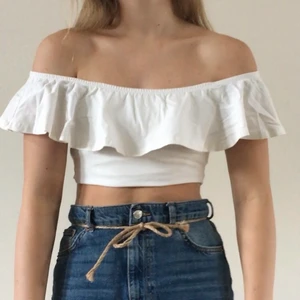 Volangtopp - Fin vit topp med off shoulder volang. På första bilden har jag vikt upp den för att få den kort. Annars är den längre. Tyget är stretchigt och skönt. 