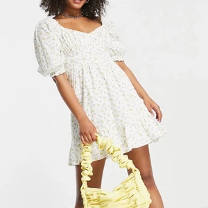 Asos somrig miniklännig - Säljer en aldrig använd klänning som är köpt på Asos från New Look i storlek eu 34. Modellen på bilden har en 36 vilket även jag har i samma klänning som sitter perfekt på min kropp (brukar pendla mellan xs-s), enlig hemsidan ska den vara ”normal passform”. Den har en hjärtformad ringning med puffärmar och rynkat bystparti, samt volanger längst ner. Yttermaterialet är 100% bomull.