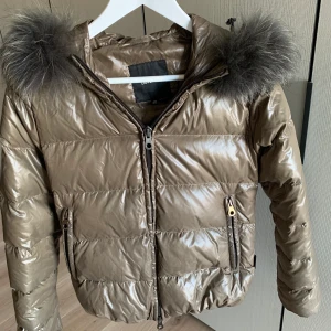 Duvetica short hooded down jacket MUD - Färg: MUD. Storlek: 40 (storlekarna är väldigt små, jackan passar mig som vanligtvis har XS/S). Jackan är i mycket bra skick. Nypris ca 6000kr.