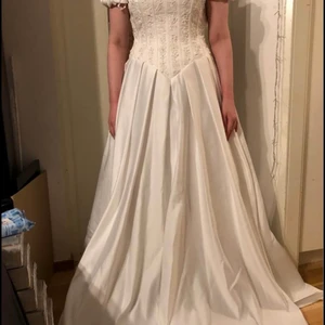 Brudklänning - Helt ny brudklänning, aldrig använd. Bara inköpt, och blev hängande i skåpet. Märke: Papillion London. Stl.36. Rålängd, ej uppsydd efter min längd. Mycket vacker! Bilderna ger inte klänningen rättvisa. Pärlbroderier, rosett på svanken, och litet släp. Vill man ha den mer klockad, kan man köpa underkjul med ring. Fraktkostnaden står köparen för, frakt ca.150kr spårbart.