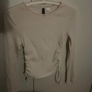 Vit långärmad tröja  - Säljer denna vita långärmade tröja vid snörning på sidan från H&M, därav inte kommer till användning.                                                                   Använd 1 gång.                                                                                 Köpare står för frakt. Fråga vid funderingar. 