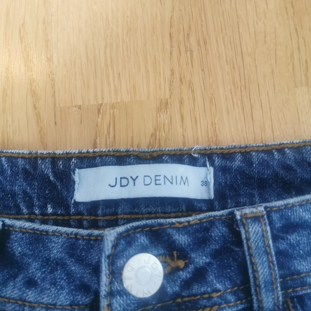 Oanvända, mörkblåa jeansshorts i storlek 38 med fransar nedtill. Fejkfickor fram men riktiga baktill. Shorts.