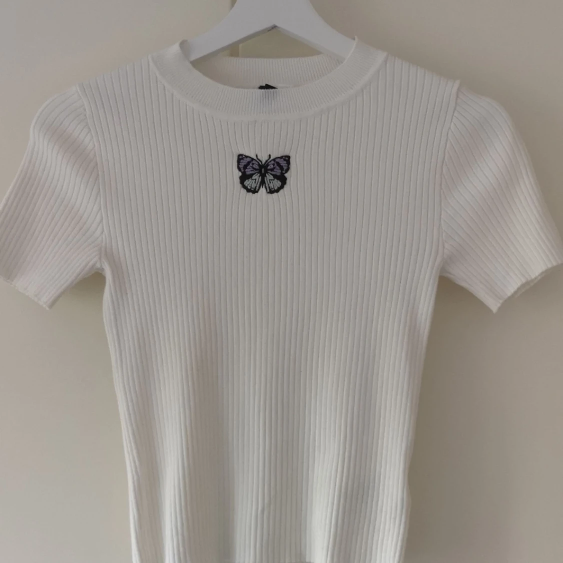 En vit topp med en fjäril på