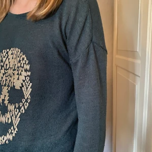 En mörkgrön dödskalletröja  - En mörkgrön dödskalletröja i stickat material. Dödskallen har en glittrig vit färg och tröjan är mörkgrön. Skönt och luftigt material. Frakt ingår. Tvättar såklart innan frakt.