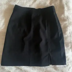 Nyköpt svart kjol med slits som inte kommer till användning. 