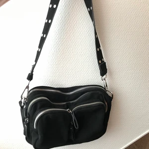 Väska  - Jättefin väska jag säljer pga att den inte används, liknar en noellabag 😇 fint skick! Det finns ett längre band som jag skickar med oxå 💕Väskan är lika lång som en Petflaska typ. Frakten står jag för!🥰 