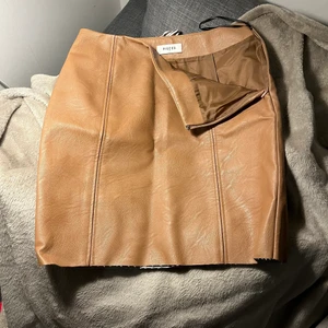 Fejkläderkjol - Fejkläder kjol från VeroModa dragkedja i sidan och sömn framtill. Når mig nästan ner till knäna, täcker alltså låren. Lite mer brun än vad bilden visar. 