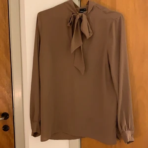 Blus - Brun snygg höstig/vintrig blus från Gina. Den är ganska luftig vilket är skönt. Knyts (eller inte) i halsen 