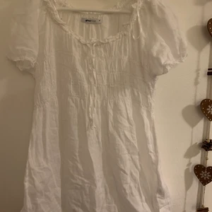 Vit milkmaid klänning - Supersöt klänning fråm Gina. Knytning upptill så man kan styra urringningen, resår över bysten. Puffiga ärmar. Lite kortare i längden så går nog inte att användas som klänning om man är över 175