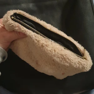 Nessesär i vitt fluffigtyg m ugglesmycke - Ca a15×20cm fluffig necessär ifrån hm. Hel och materialet är oförändrat trots att den hängt med ett par månader. Har själv piffat upp den med ett smycke av en uggla i dragkedjan. Perfekt storlek för dagens sminkatteraljer