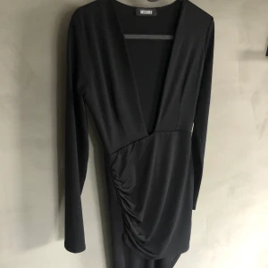 Missguided klänning XS - Superfin svart klänning från Missguided med djup urringning och snedskuren kjol. Storlek 34. Aldrig använd, endast provad. Frakt tillkommer på 66kr spårbart. Skriv om ni vill se fler bilder. 