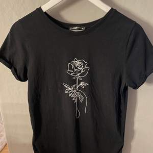 En svart T-shirt med en ros på. Köpt på Newyorker. Strl M men liten i storleken. 15kr+66kr frakt = 81kr