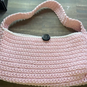 Virkad väska - Hand gjord axelväska av fint garn! Rosa med vit kant runt öppningen. Super smidig och lätt! Stängs med en knapp! Är flera intresserade blir det budgivning!                                Mönster av @crochetgal100