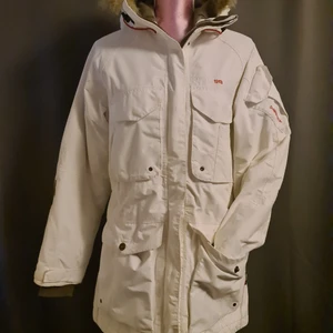 Didrikson strl 36 - Snygg jacka i vitt från Didrikson i strl 36. Borttagbar fuskpäls på luvan, varm och skön. Fint använt skick.