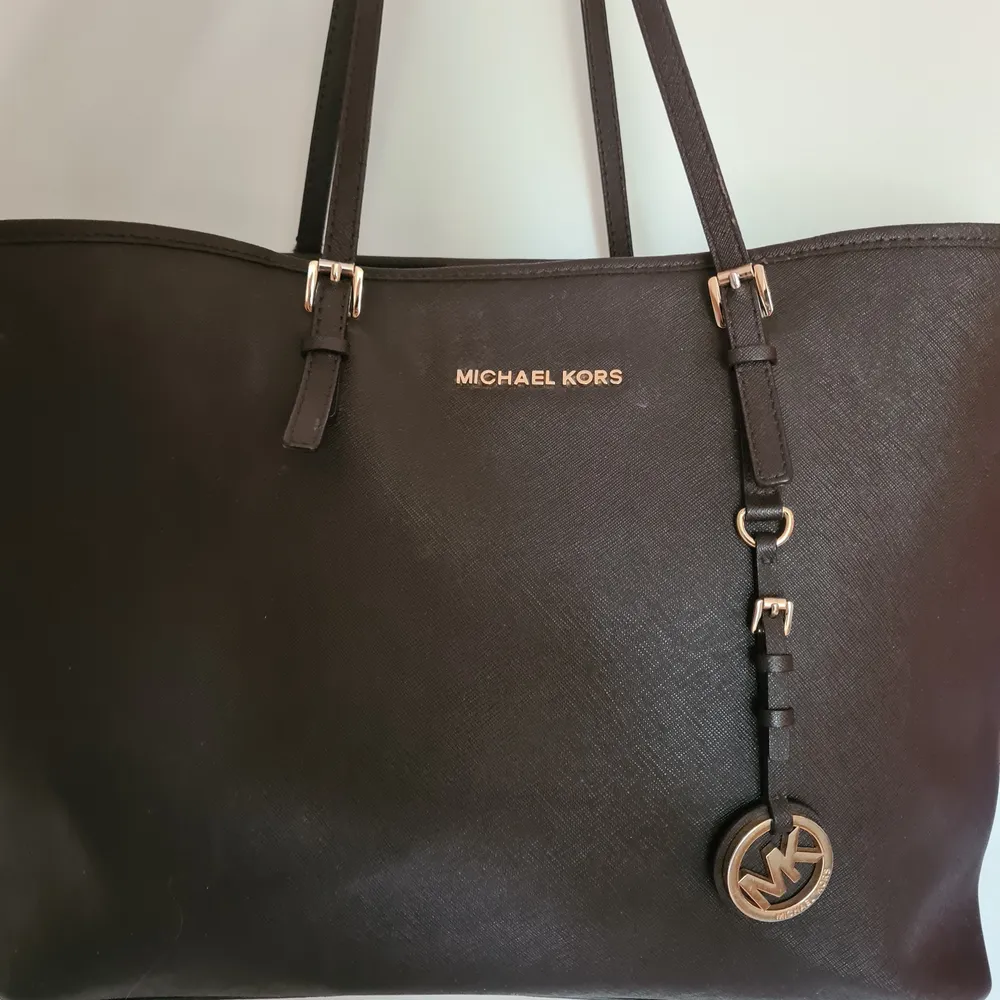 Mörkbrun MK väska, äkta. Är väl använd, kan ses på handtagen samt att ena spännet har lossnat på baksidan utav väskan. Annars hel, inga repor eller dylikt.. Väskor.