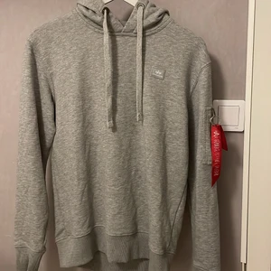 Hoddie - Fin hoddie som är använd en hel del därav är märket på det röda bandet utsuddad (bild 1,2) den lilla metall ringen som satt på röda bandet ur(bild 2) och den är lite nopprig men annars är den väldigt fin så den är i använt skick! I storlek XS/S och kanske till och med en liten M