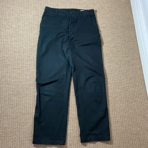 Hope chinos byxor  - Svarta byxor från Hope. Raka byxor men är lite ”flared” nertill. Använda byxor, super härligt material och sköna byxor nu till sommaren. På bakfickan fattas en knapp till fickan. 