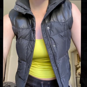 Äkta dunväst med skinndetaljer - Superfin väst från Boomerang i lite matt material. Äkta naubuk-läder upptill och en stickad lite högre krage. Använd men i superbra skick, inga defekter.