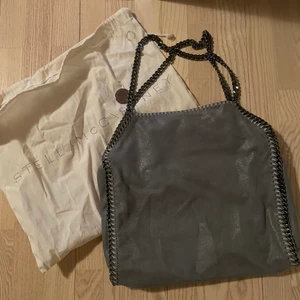 Stella maccartney shoulder bags - Stella McCartney Bag Grå Falabella kedjetrimmad tote väska från STELLA MCCARTNEY med kedjelänk, magnetfäste, logotyp charm, invändig ficka med dragkedja och foder med logotryck. Väskan är nästan som ny skick har knappt använt den.