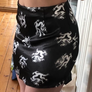 Svart satinkjol med drakar - Svart satinkjol med vita drakar! Ljusrosa dragkedja, sytt sjölv. 