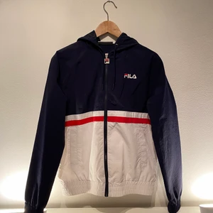 FILA Regn/Vind Jacka  - Jag säljer min FILA jacka som jag i stort sätt aldrig haft på mig ! Plagget är i nyskick, väldigt bra kvalite samt super snygg. Storlek - S, kan dock även passa någon med storleken XS. Plagget funkar bra för både killar och tjejer. Kontakta mig vid fler frågor ! 
