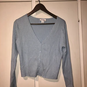 Topp från Monki - Ljusblå topp från Monki. Storlek XL, men tröjan är fortfarande kort över magen. Väldigt skönt material och kan användas både som kofta eller tröja. Använd en gång.