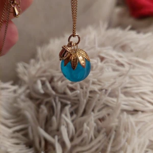 Halsband - Halsband 26cm långt. Turkosblå glaskula fäst i guldblad med litet ekollon.