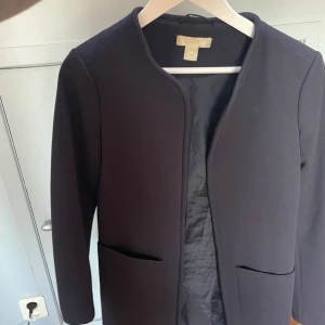 Kappa storlek 36 - Mörkblå tunn kappa från H&M. Köpt för flera pr sedan och har används en del. Väldigt lite slitage, och kappan är i gott skick. Slutar ca 1dm ovanför knät på mig som är 169cm. Ingen knäppning. 