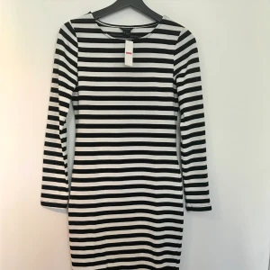 Svartvit randig klänning OANVÄND! - Svart och vitrandiga klänning från Lindex Strl S Helt oanvänd med prislappen kvar! Klänningen är figursydd och sitter lagom tajt kring kroppen.  Passar perfekt till kyligare sommarkvällar eller till hösten  Köpt för 299kr men säljer den för halva priset!  Jag samfraktar gärna!