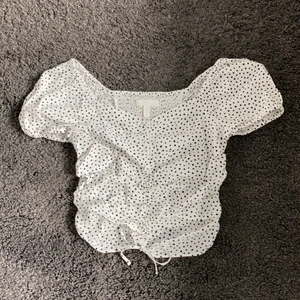 Prickig blus - Prickig blus med puffärmar och en liten snörning nertill. Har resår bak. Endast en liten fläck inuti toppen (bild tre), annars som ny.