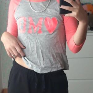 Tröja med tryck - Ljusgrå tröja med neonrosa tre kvarts ärmar och tryck i samma färg av texten "omg". Snygg och utan defekter.