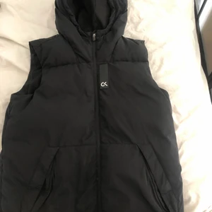 Calvin Klein väst - Schysst och unik dunväst från Calvin Klein, använd men i bra skick. Passar perfekt nu till vår/sommar.