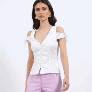 Vit korset topp med rosetter 🤍 - Vit korset topp med rosetter från nakd i storlek 38, använd en gånge så den är i bra skick, fin till sommaren 🤍 80kr+ frakt 📦 