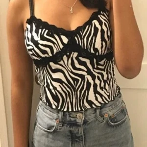 Zebra randig topp  - Jag säljer denna gulliga topp pågrund av att jag inte har användning av den längre. Har använt den ett fåtal gånger och är inte sönder på något sätt och har inga fläckar. Kvaliten är bra även fast materialet är tunt. Man kan justera hur tight den ska sitta ifall man tycker att den är lite lös. Funkar även jättebra att kanske ha en tight tröja under såsom en vit turtleneck(: ser bra ut på både stora och lite mindre bröst. Köpte den från SHEIN för ett tag sedan så därför bestämmer jag för att sälja den billigare🌸 kontakta mig för mer information💕 (inte jag på bilden) 