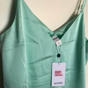 Lång grön satin klänning från Monki - Helt ny! Oanvänd med lapp kvar. Justerbart. Passar även en S eller L beroende på passform.  Strl M