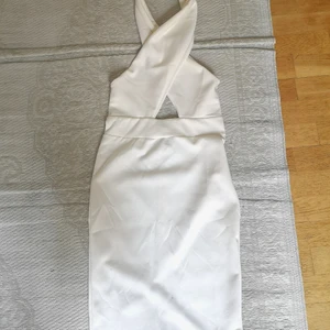 Oanvänd knälång elegant klänning - Materialet är bomull och polyester. Halterneck. Dubbelt tyg i bröstdelen så den täcker bra. Liten slits längst ner bak på kjolen. Elegant och snygg! Aldrig använd för har bara aldrig blivit tillfälle och nu har jag vuxit ut den. 